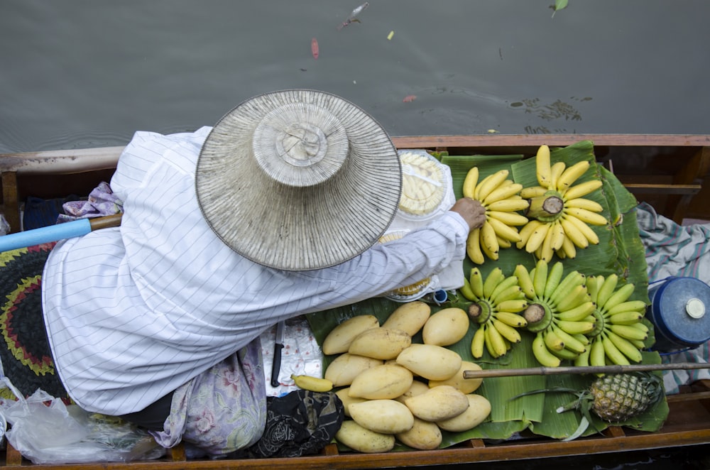 person in boat floating on body of water with fruits