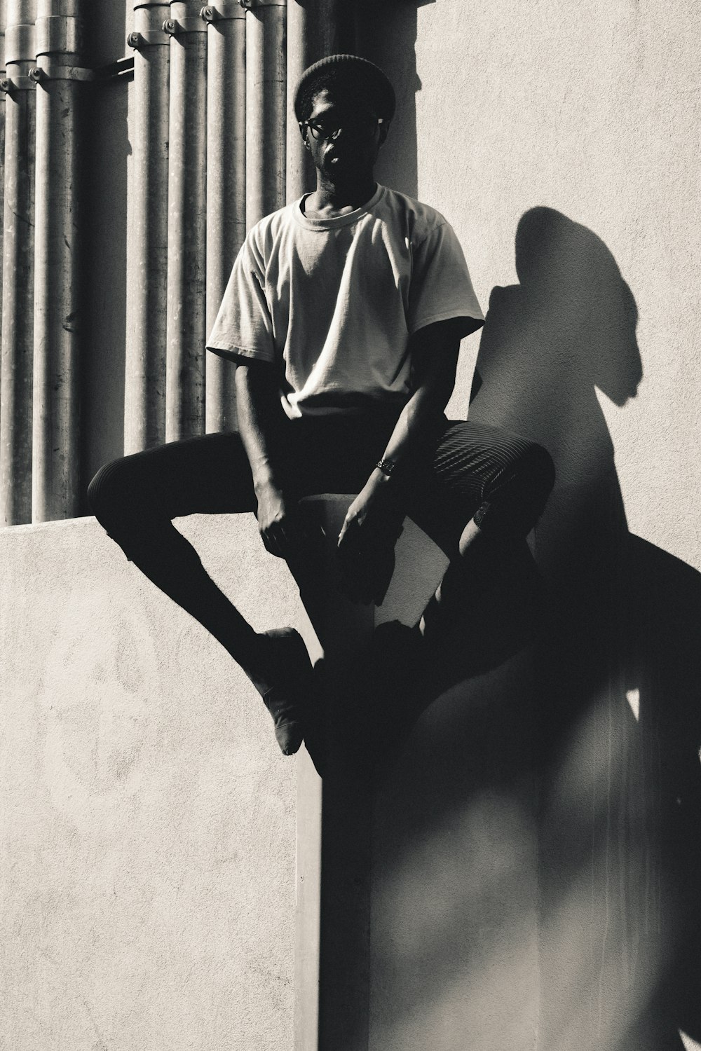 grayscale photo of person sitting on concrete pavement