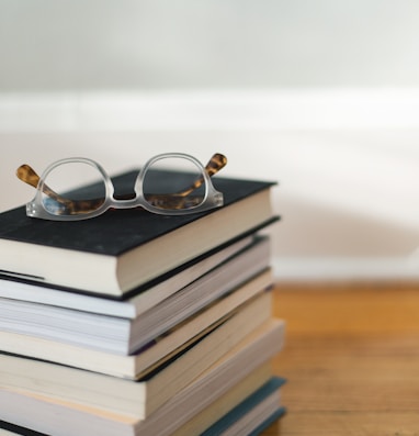 clear framed eyeglasses on top of pile of books