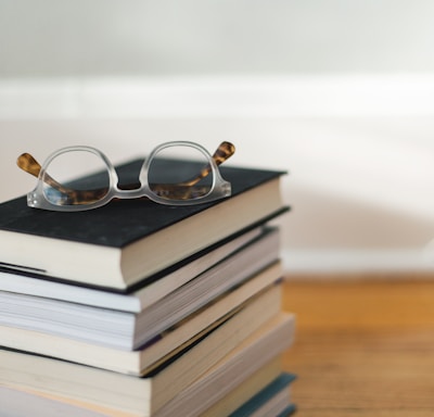 clear framed eyeglasses on top of pile of books