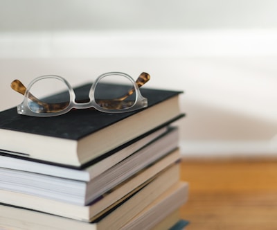 clear framed eyeglasses on top of pile of books