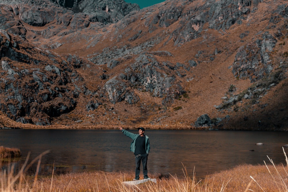 person standing in front of body of water near mountain