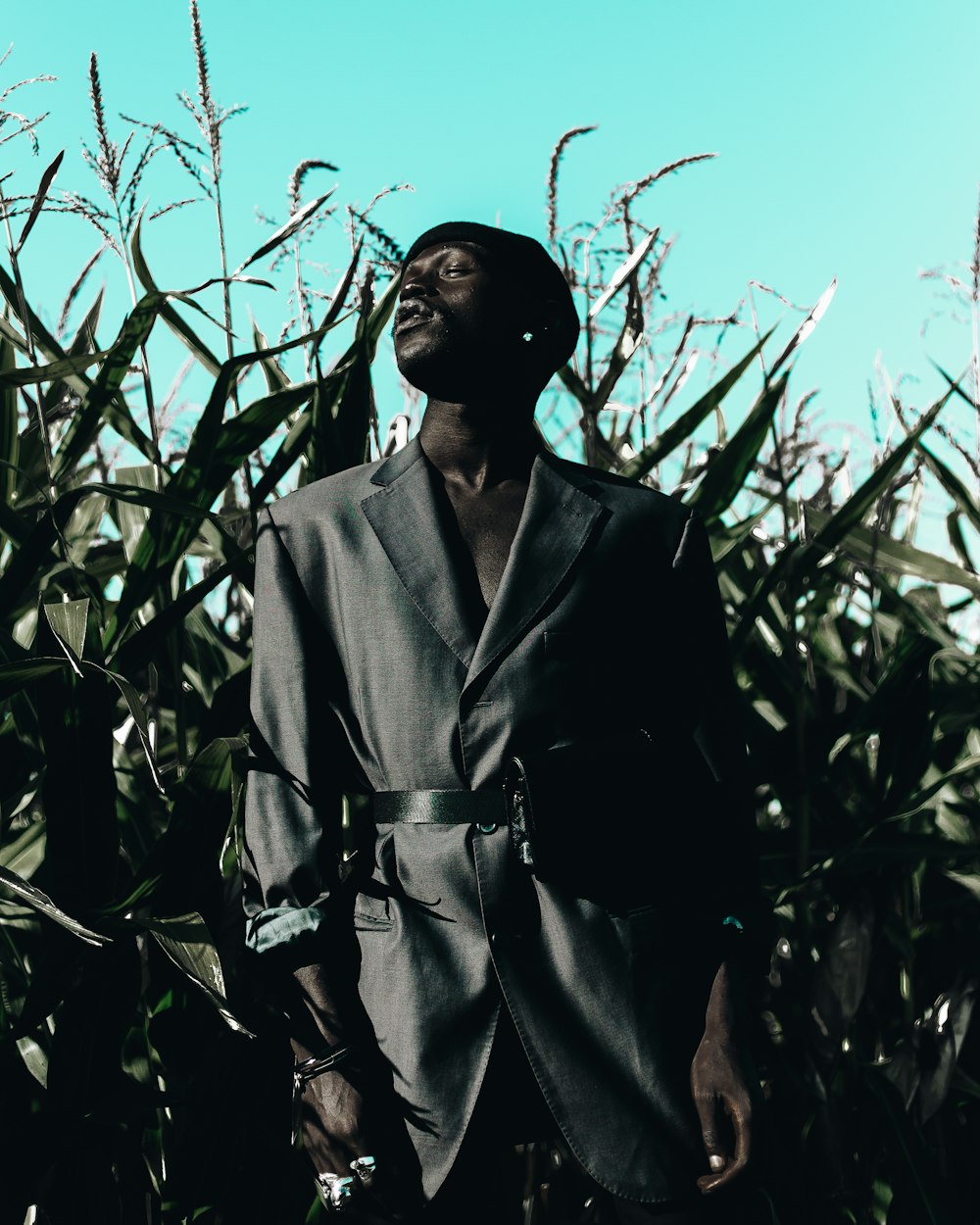 man in suit jacket standing near green leafed plants