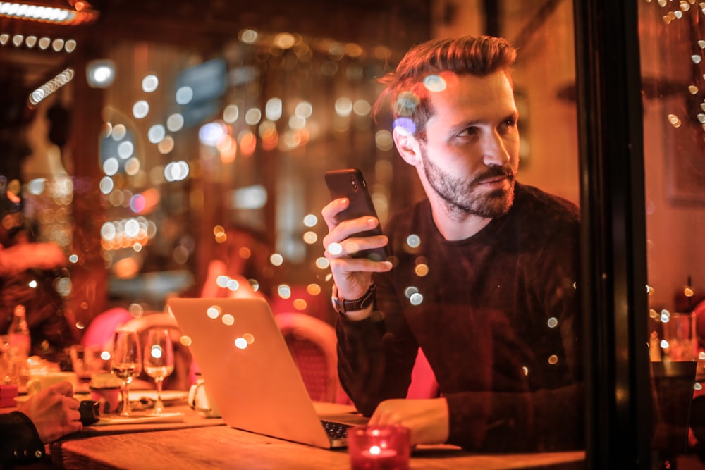 man holding smartphone beside table