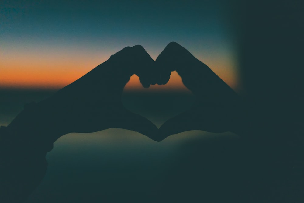 silhouette photography of heart form hands