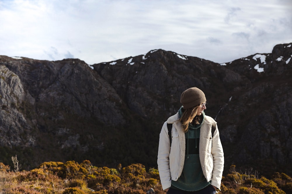 man wearing white jacket on cliff under white sky during daytime