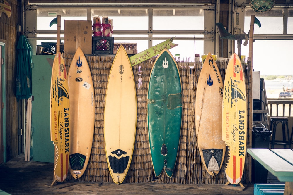 six assorted-color surfboards on brown board