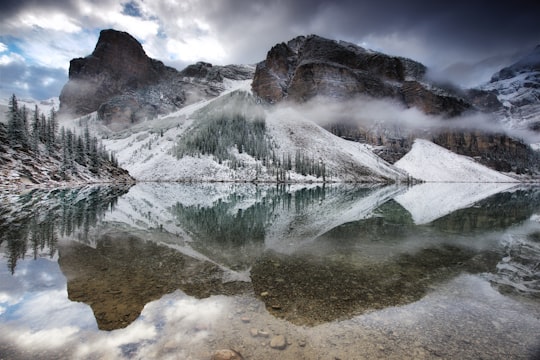 mountains reflecting on body of water in Moraine Lake Lodge Canada