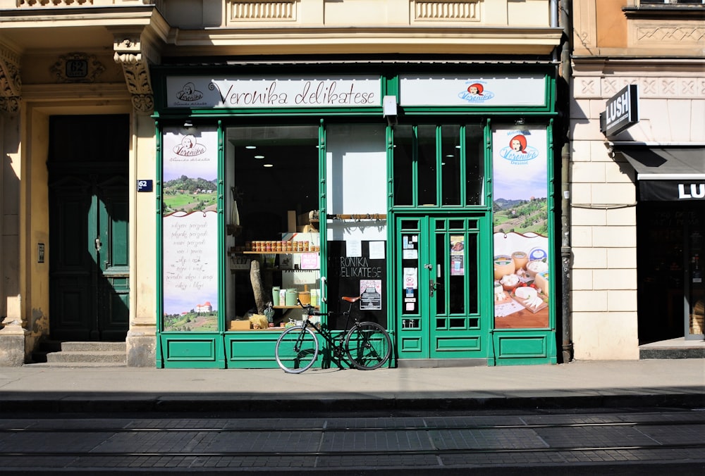 black bicycle parked in front of green store facade