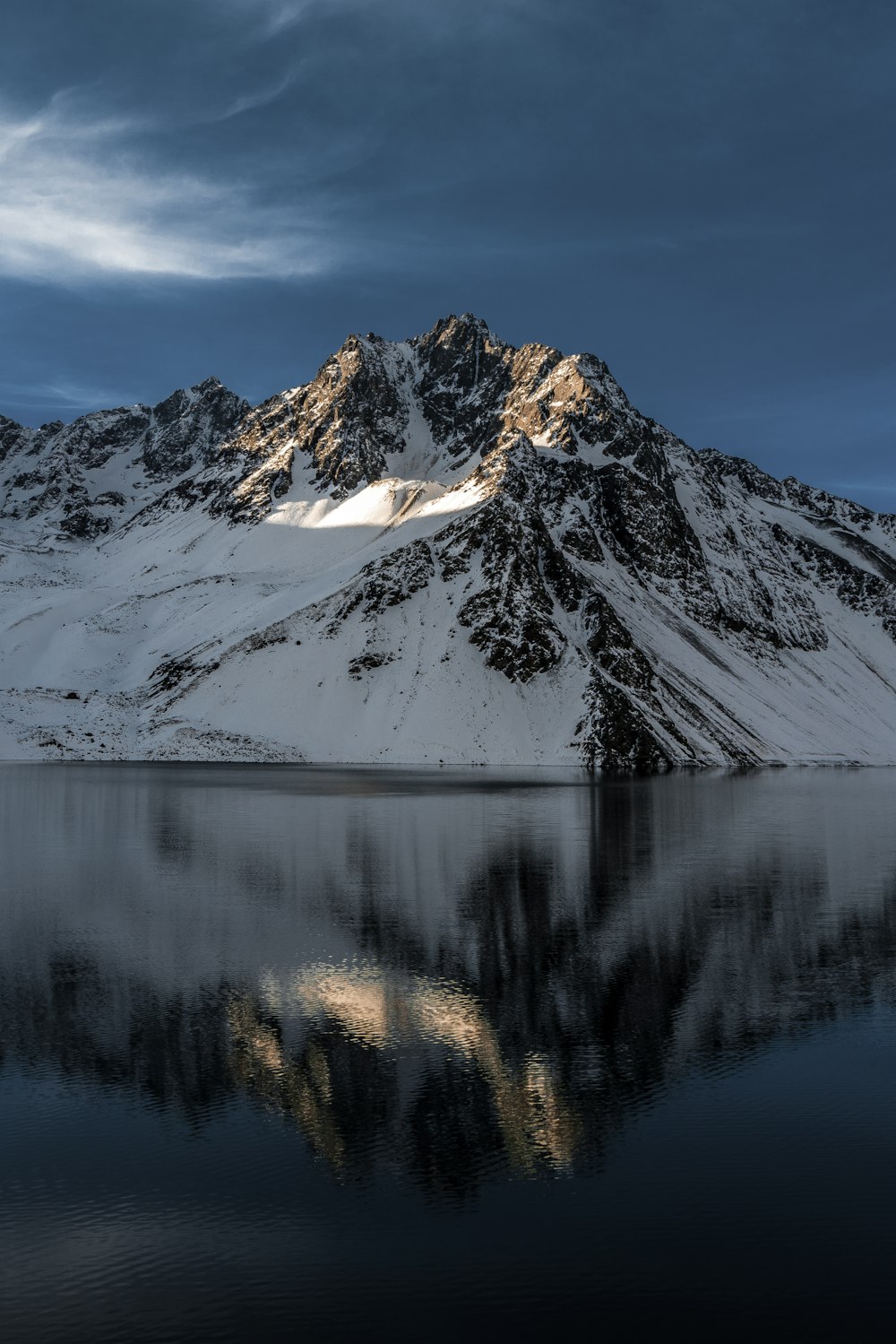 body of water near mountain coated by snow