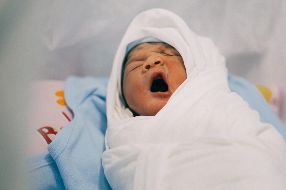 baby yawning on blue textile