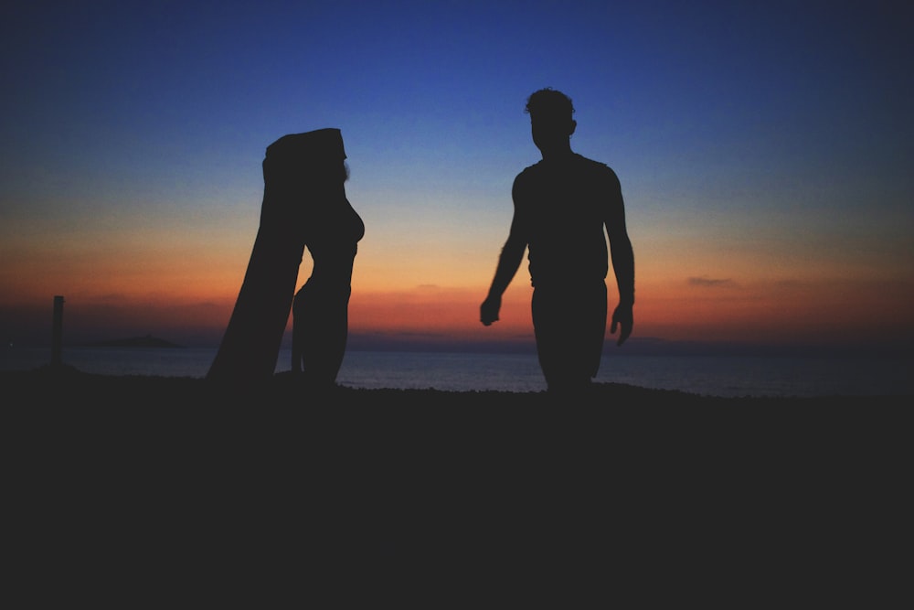 silhouette photo of man and woman near beach