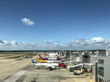 A tanker truck unloading jet fuel at a busy airport terminal under a clear blue sky.