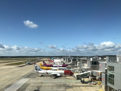 A panoramic view of multiple airplanes lined up at the Munich Airport gates under a clear blue sky.