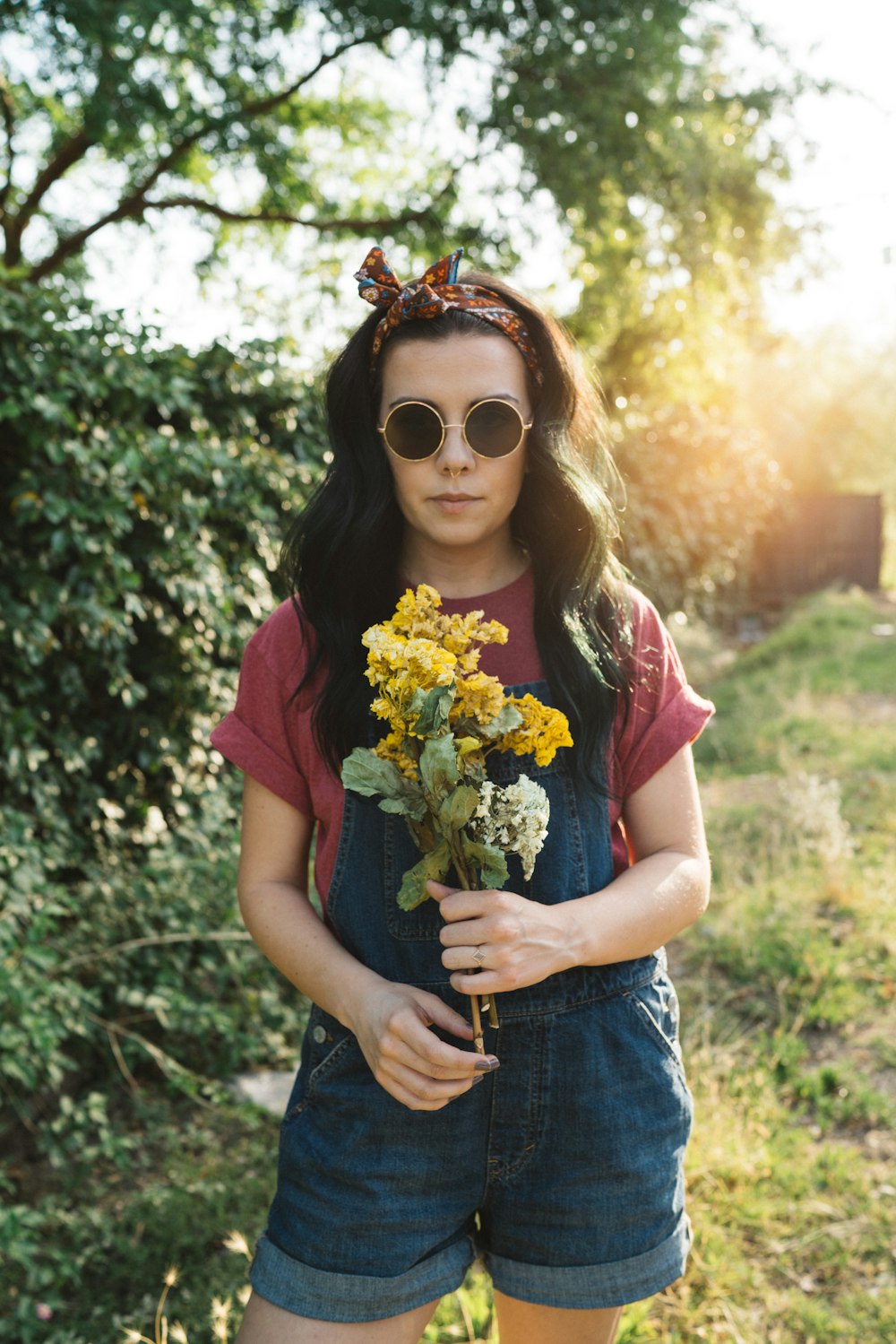 girl holding yellow petaled flowers wearing blue denim shortalls