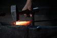 man pounding hammer on hot iron rod