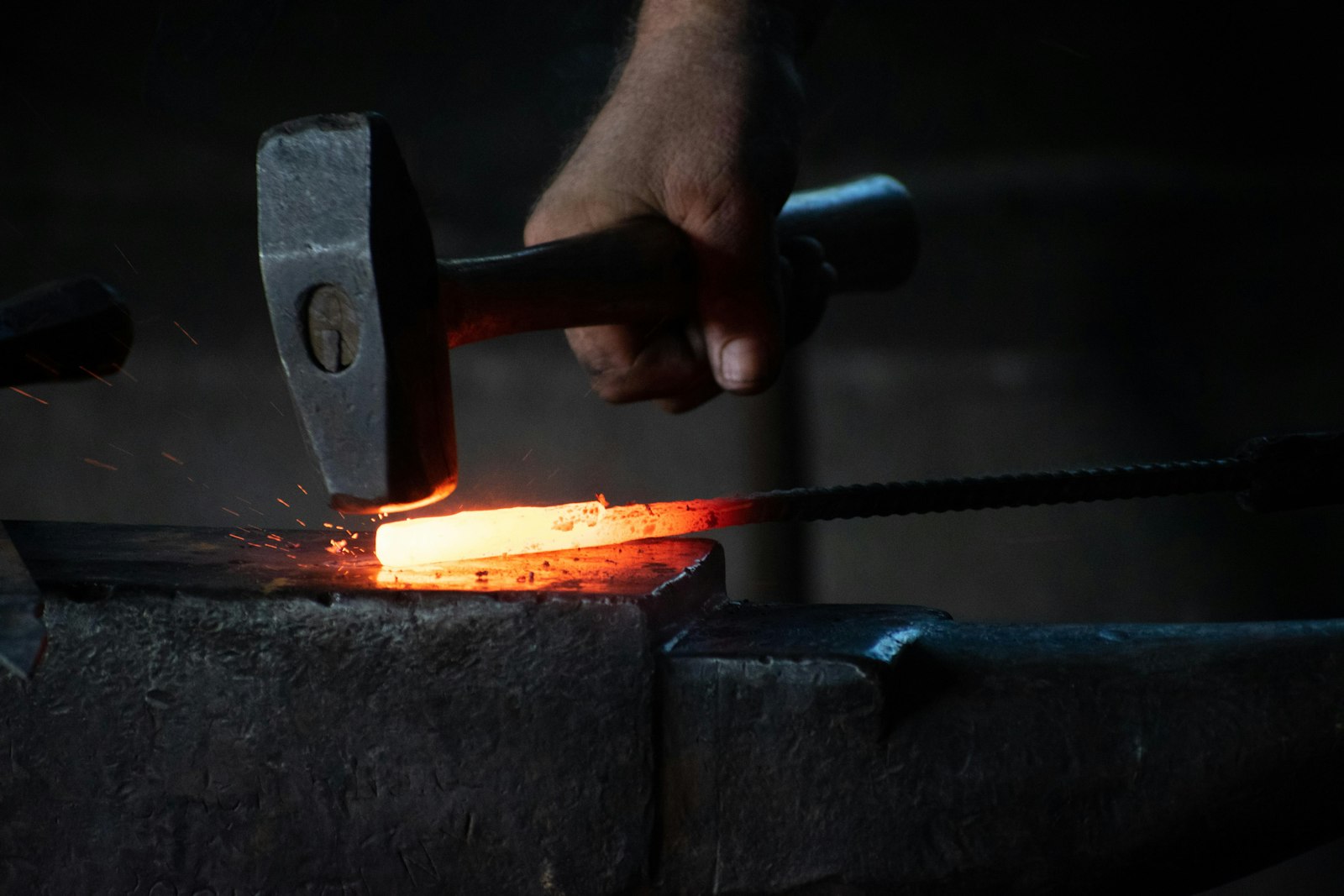 Smith hammering glowing steel on the anvil