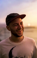 Close-up of a model wearing a soft, bright track pant and matching cap, smiling against a sunny urban backdrop.