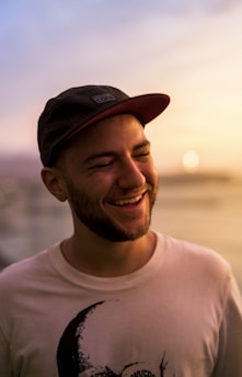 Close-up of a woman smiling warmly, wearing Sekille apparel with a sporty cap, with a cityscape behind her.