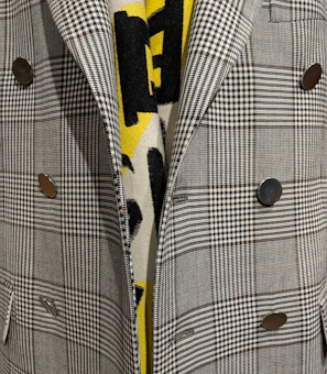 Close-up of a finely stitched navy blazer with gold buttons on a mannequin.