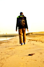 A happy traveler exploring a beautiful, sunny beach with a backpack.