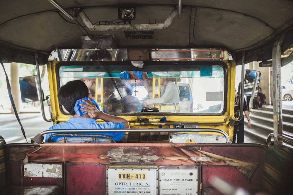 man riding yellow and gray autorickshaw during daytime