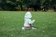 A child wearing a bright green écospotif jacket playing soccer on a grassy field.