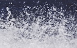 A dynamic spray of water droplets suspended in the air against a dark background, capturing the motion and energy of splashing water.