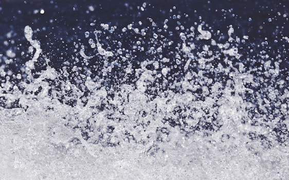 A dynamic spray of water droplets suspended in the air against a dark background, capturing the motion and energy of splashing water.