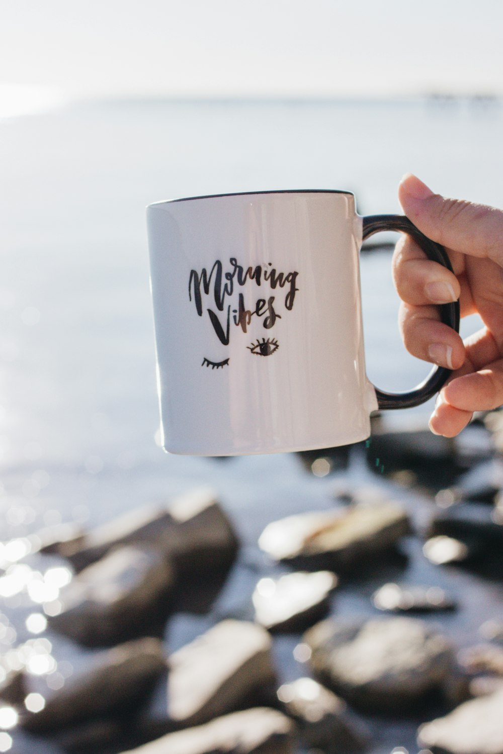 person holding white morning vibes-printed mug