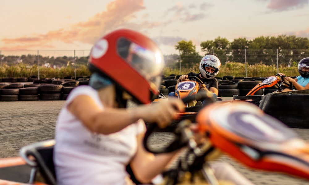 woman riding on orange and black ride-on car toy during daytime