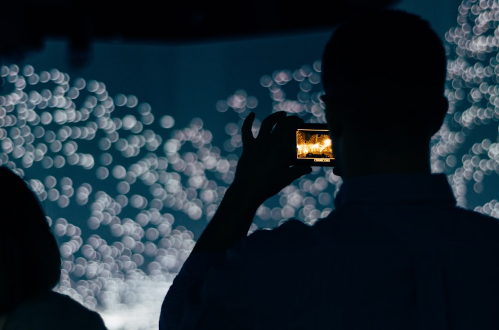 silhouette of person holding smartphone displaying bokeh lights