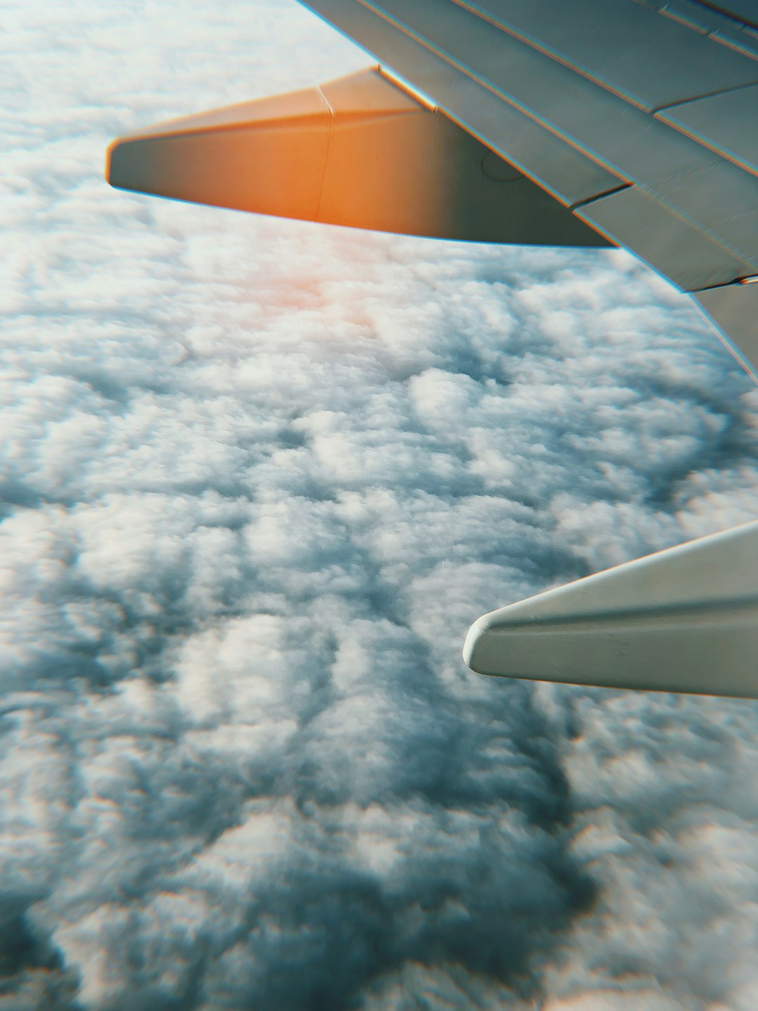 gray airplane wing above white clouds