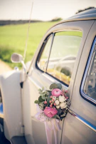 An elegant vintage Rolls Royce with white floral arrangements on the hood.
