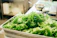 A happy woman holding a crisp green lettuce in a bright, clean kitchen.