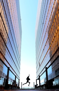 A happy young man jumping in the air with a bright city street behind him, symbolizing financial freedom.