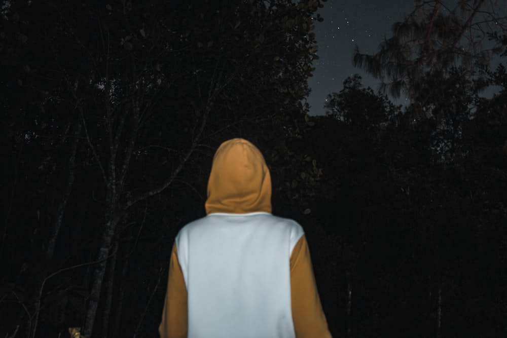 man wearing white and yellow hoodie under trees