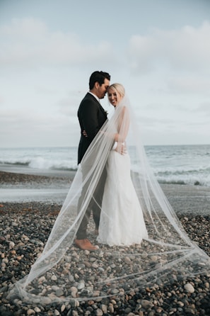 Bride and groom under veil on an Ayrshire shoreline—cinematic wedding videography near Glasgow