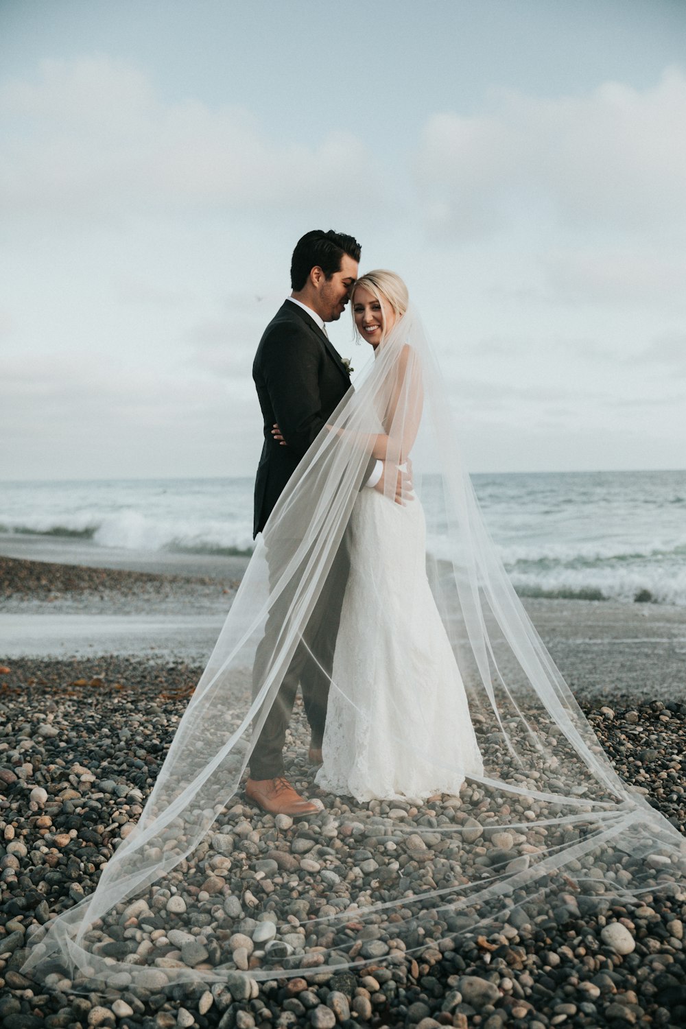 newly wedded couple standing on shore during daytime