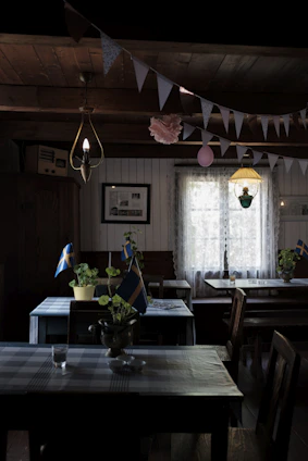 A warm, Scandinavian-style restaurant interior with a rustic wooden table set for a meal, bathed in soft natural light.