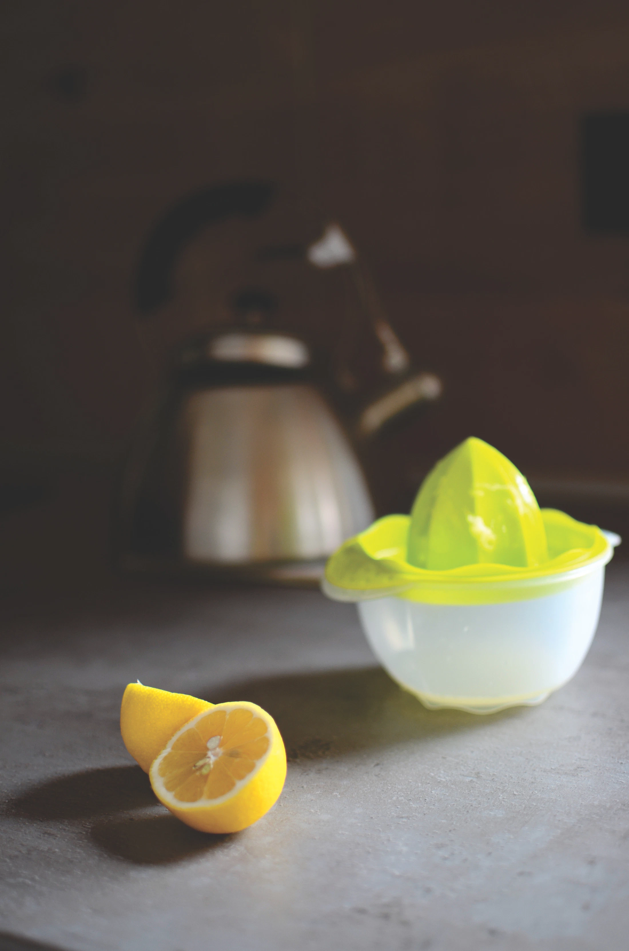 Lemons beside a citrus juicer in a softly lit kitchen setting