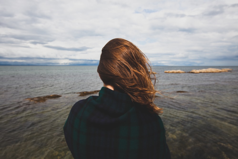 photography of woman standing near body of water during daytime