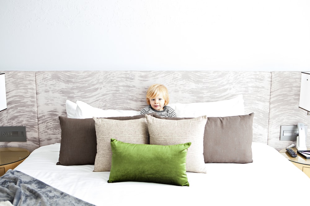 boy on bed front of pillows at daytime