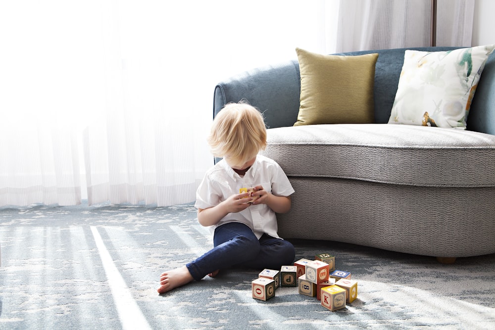 boy sitting on floor playing blocks near couch