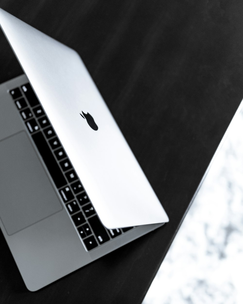 opened silver MacBook on black wooden surface