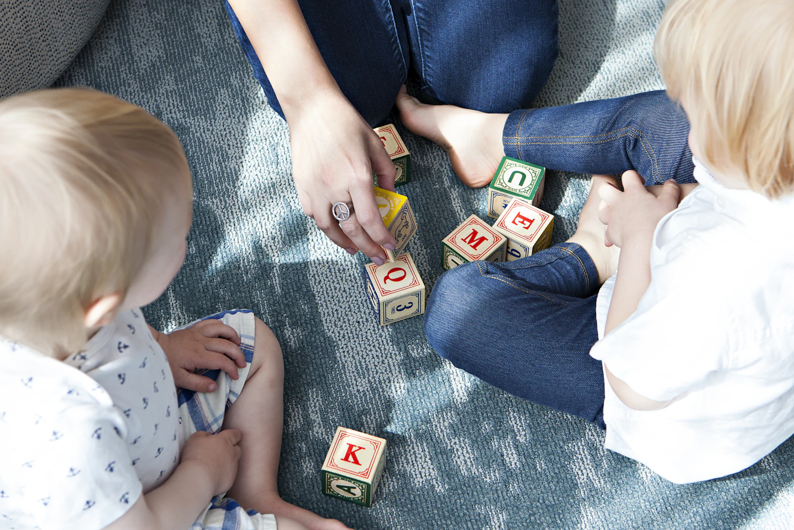 Two toddlers playing with letter cubes on the floor