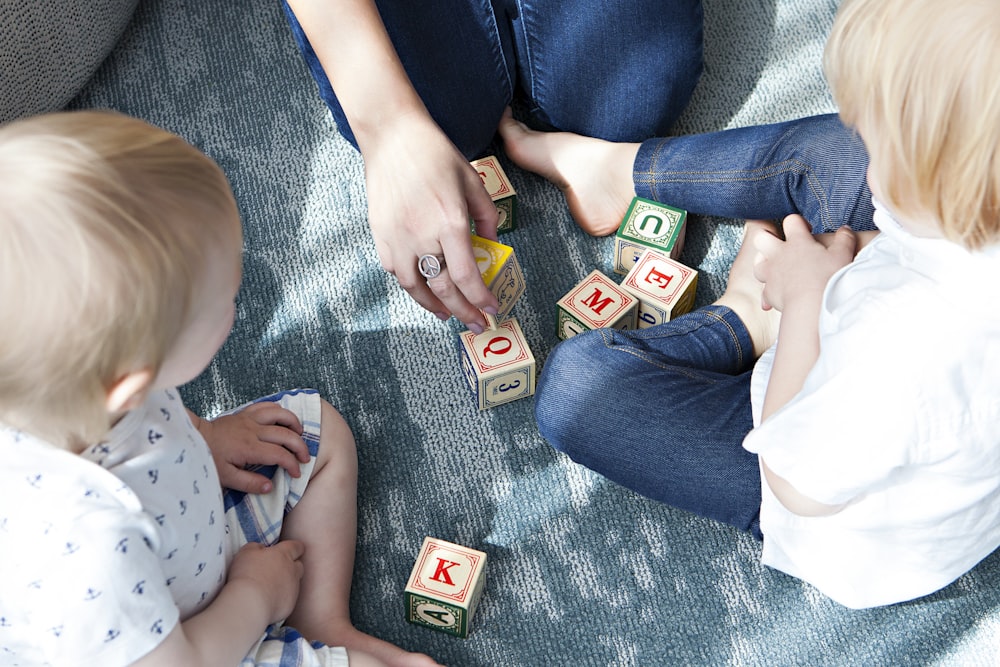 two toddler playing letter cubes with their mom co-living with kids