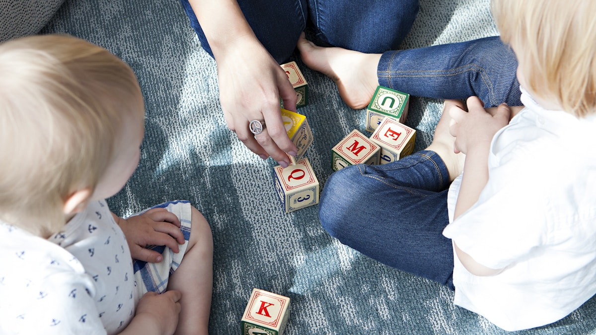 two toddler playing letter cubes