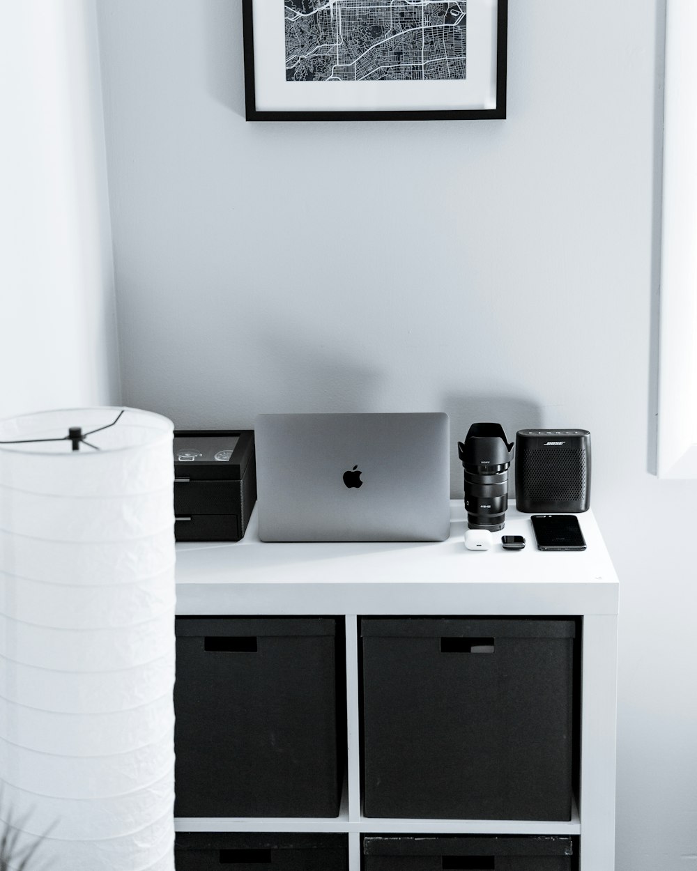silver MacBook beside black camera lens and speaker on dresser