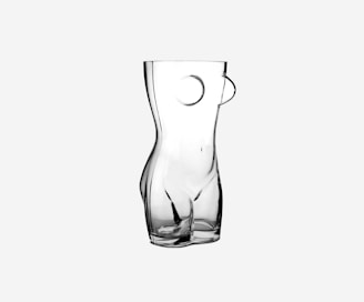 A sleek, matte black vase with bold geometric curves sitting on a minimalist white pedestal.